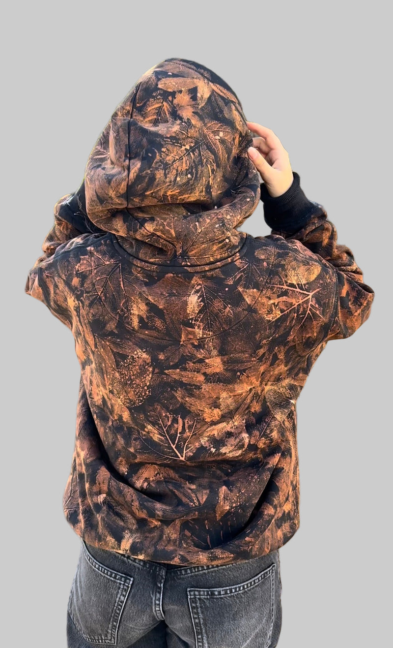 Person wearing a brown camouflage hoodie on a gray background