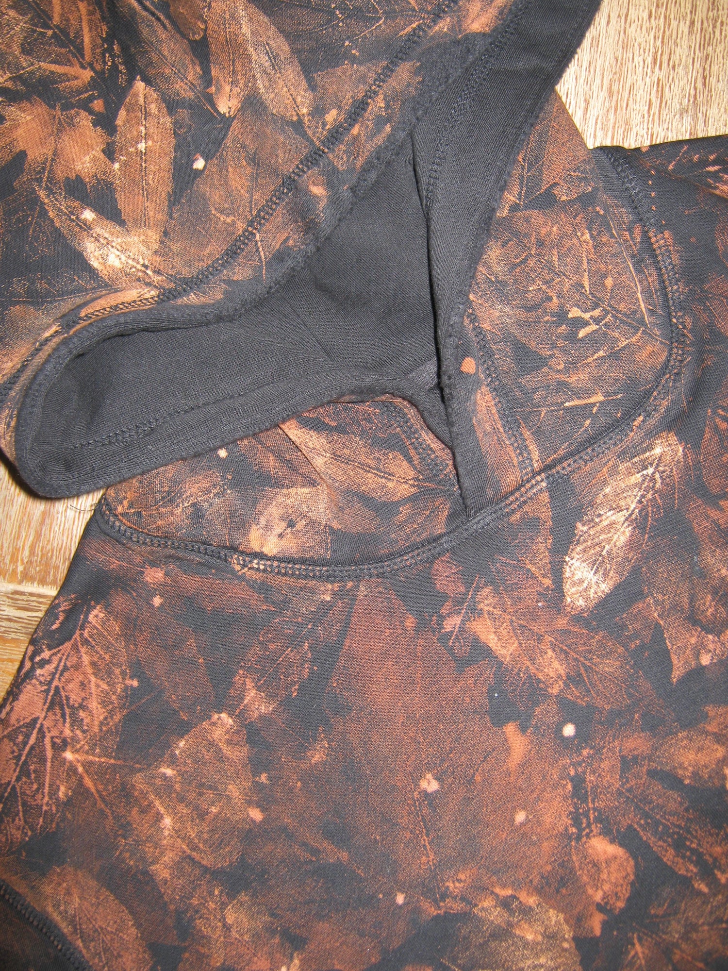 Close-up of a black garment with a brown leaf pattern on a wooden surface
