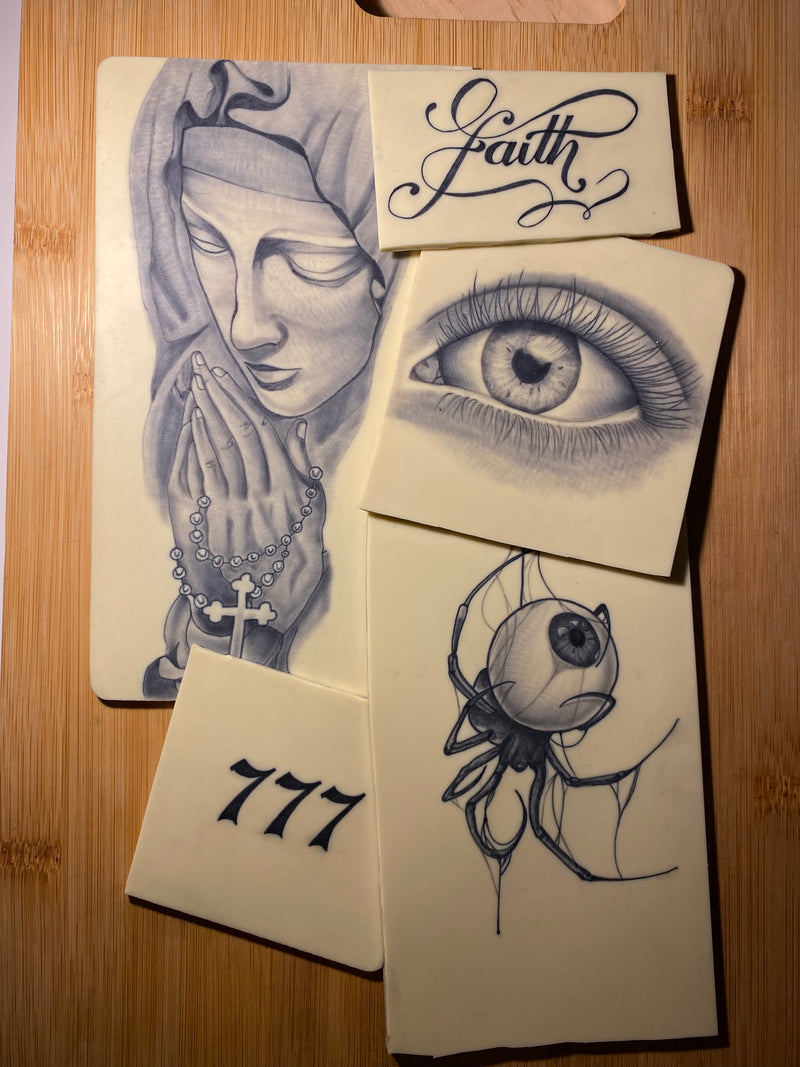 Collection of tattoo designs on fake skin with 'Faith', '777', an eye and spider, Algarve.