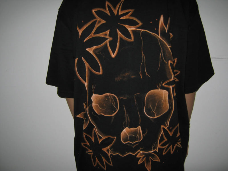 Black t-shirt with orange floral and skull design on a plain background