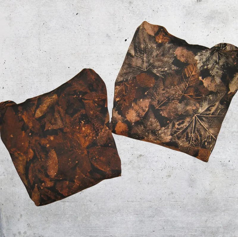 Two hoodies with leaf patterns on a gray concrete surface