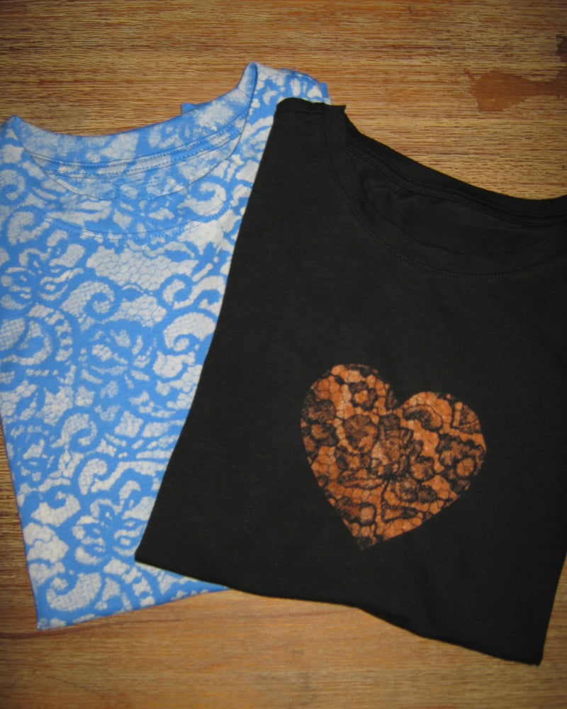 Black tank top with a heart design and blue lace patterned top on a wooden surface